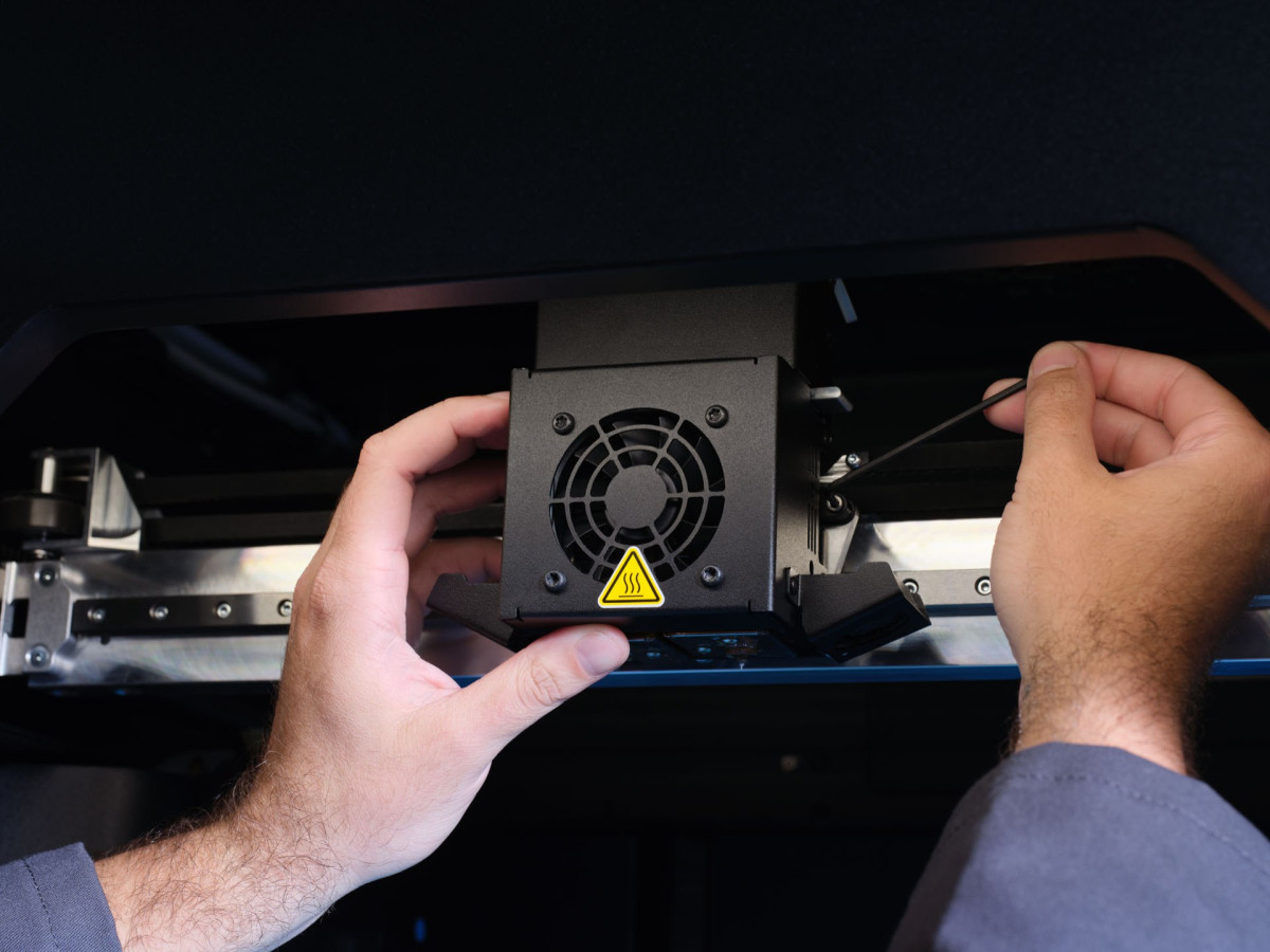 a metal 3d printer print head being removed by an engineer